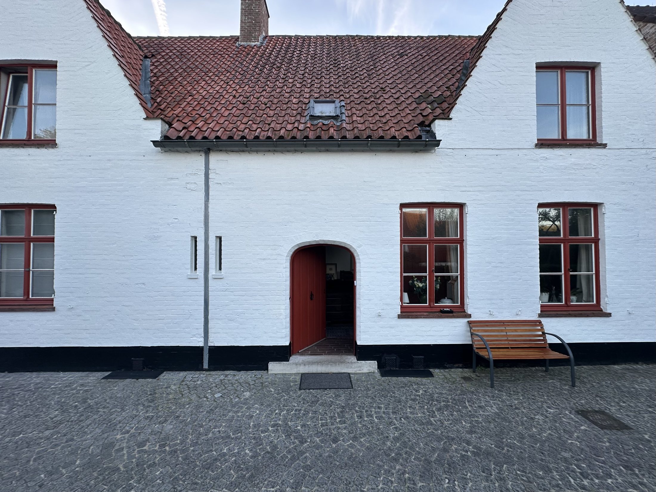 De voorgevel van Speystraat 3 met witte gevel, rode deur en luiken en twee puntgevels