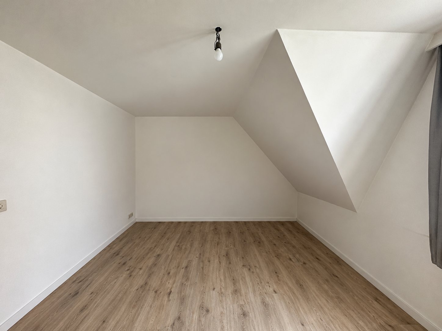 De lege kamer met schuine wanden en dakkapel